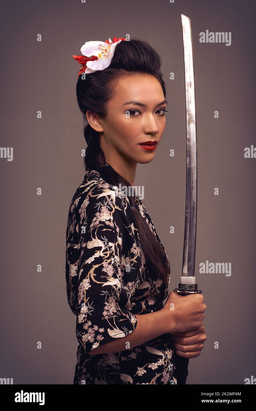 Shes unrivaled with a sword. Studio shot of an attractive young woman holding a samurai sword. Stock Photo