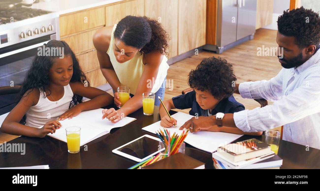 Play an active role in your childs homework. Cropped shot of parents helping their two children with their schoolwork at home. Stock Photo