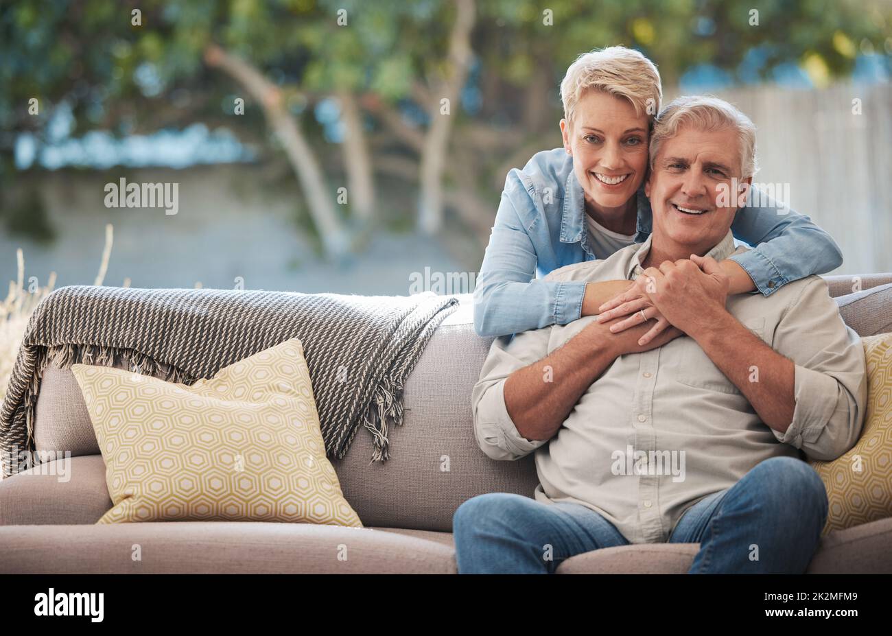Mature couple, love bond and hug on house patio, home garden sofa and relax furniture chair in backyard. Portrait of smile, happy and retirement Stock Photo