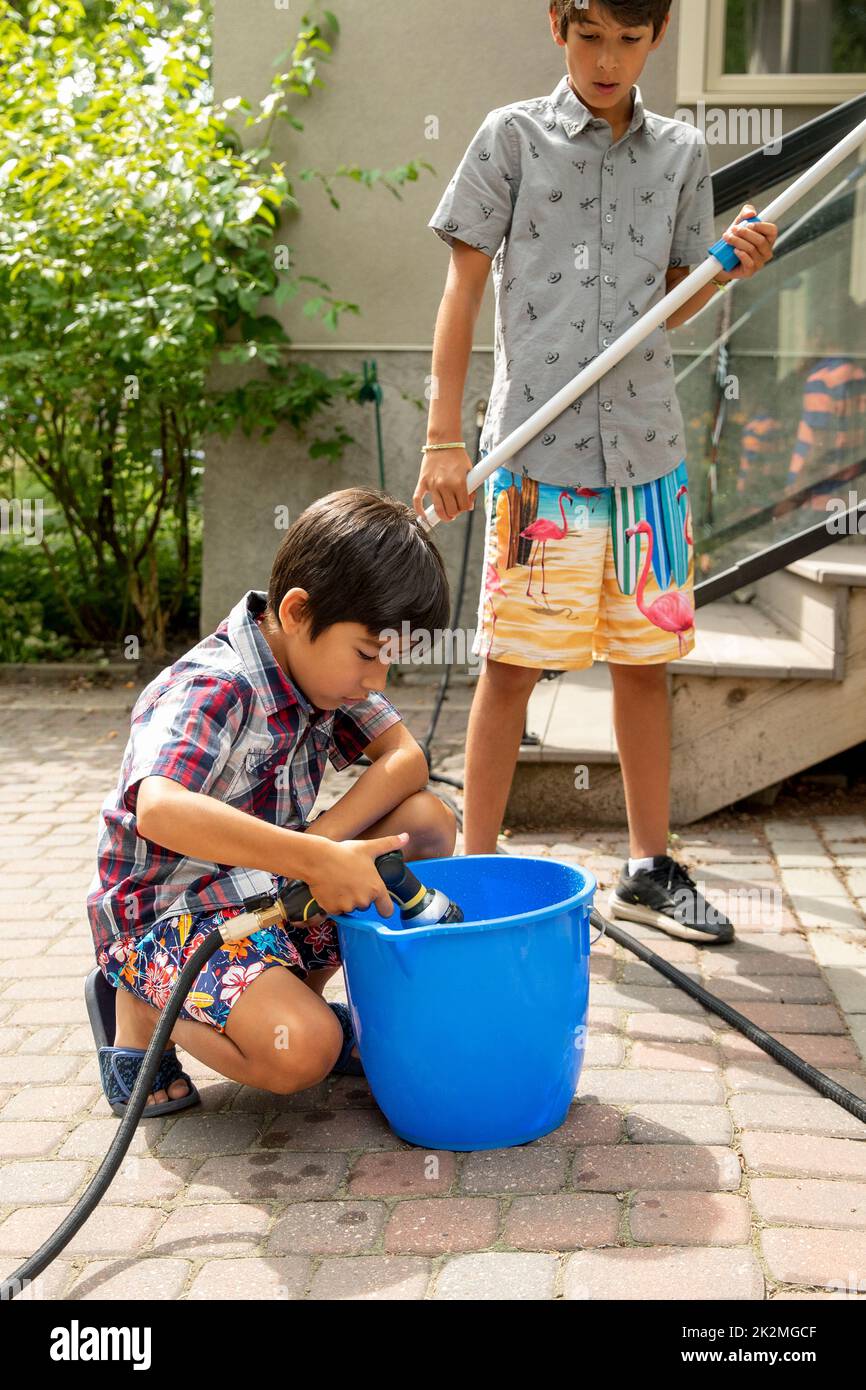 Boy filling up pail with water in backyard Stock Photo Alamy
