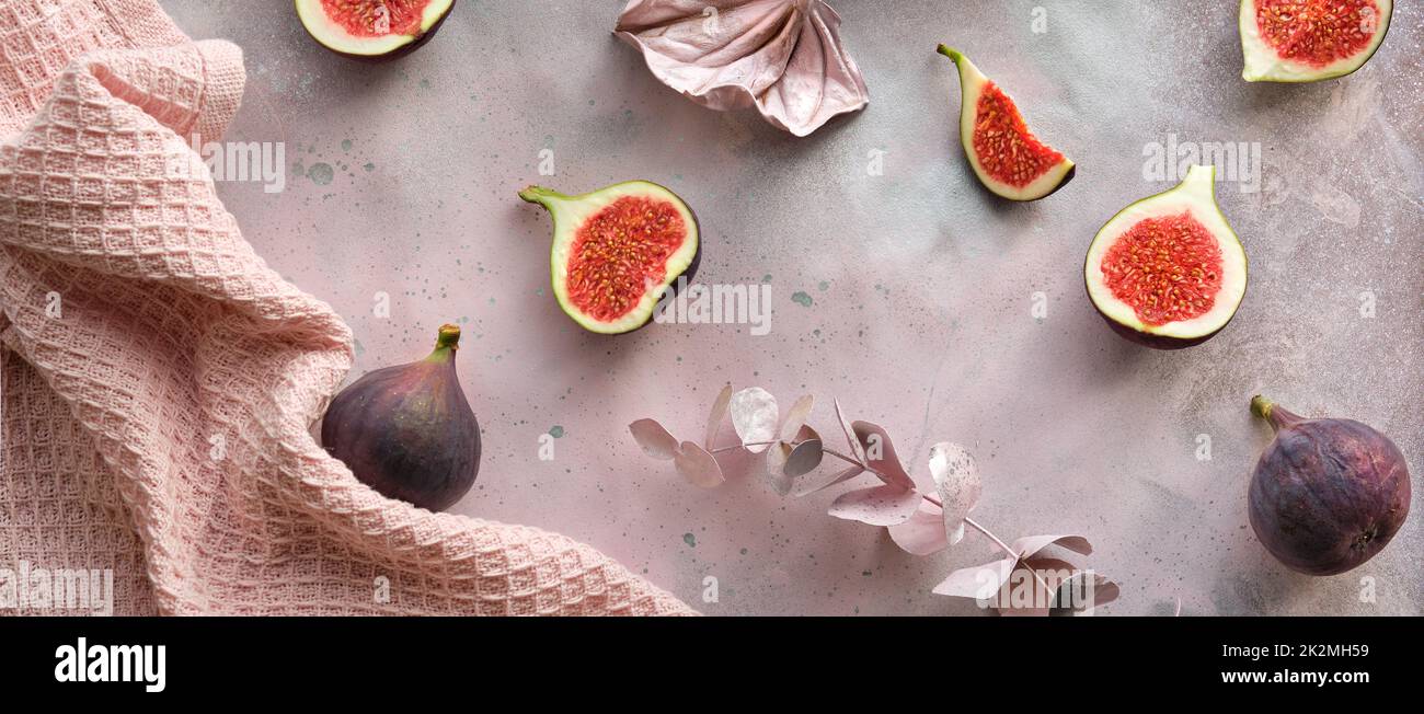 Fresh halved fig fruits and dry euvalyptus and cala lily flowers painted metallic pink on bstract textured background. Stock Photo