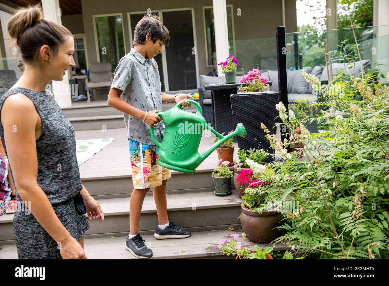 Boy watering plants in backyard Stock Photo Alamy