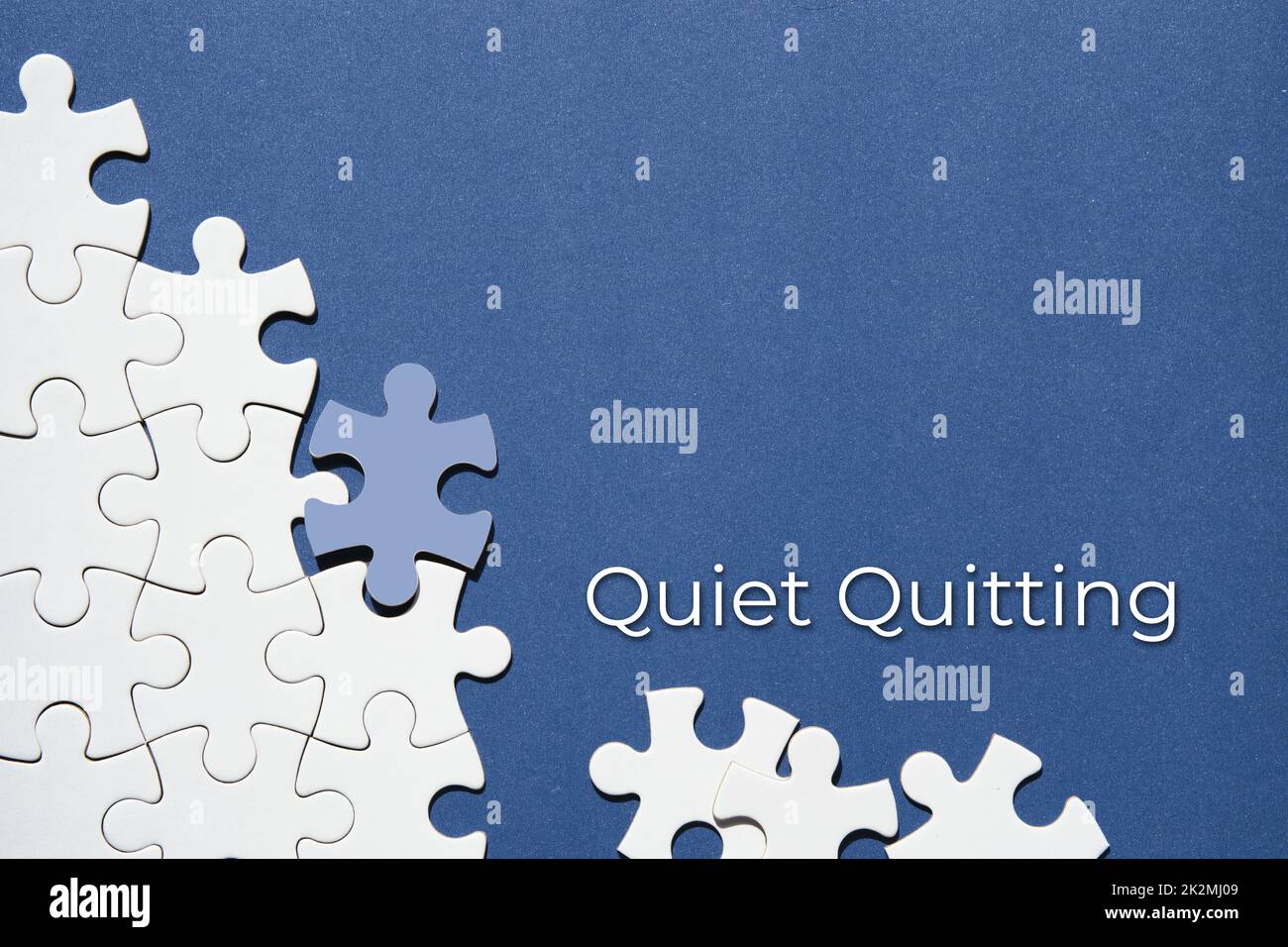 Quiet quitting text, caption. Jigsaw puzzle pieces half assembled and separate.Top view, flat lay, blue white paper background. Stock Photo