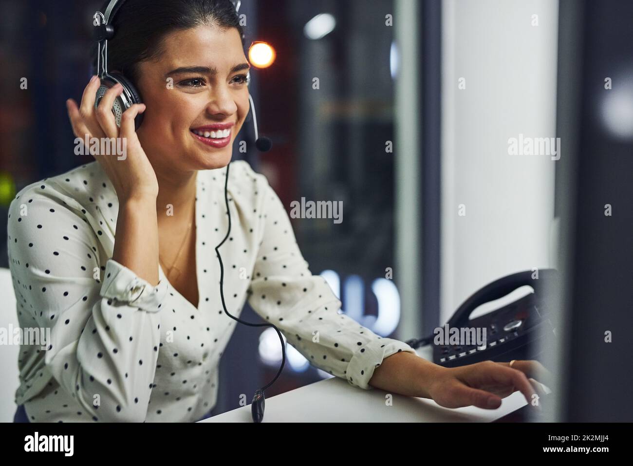 Every call is dealt with professionalism. Shot of a young call centre agent working late in an office. Stock Photo