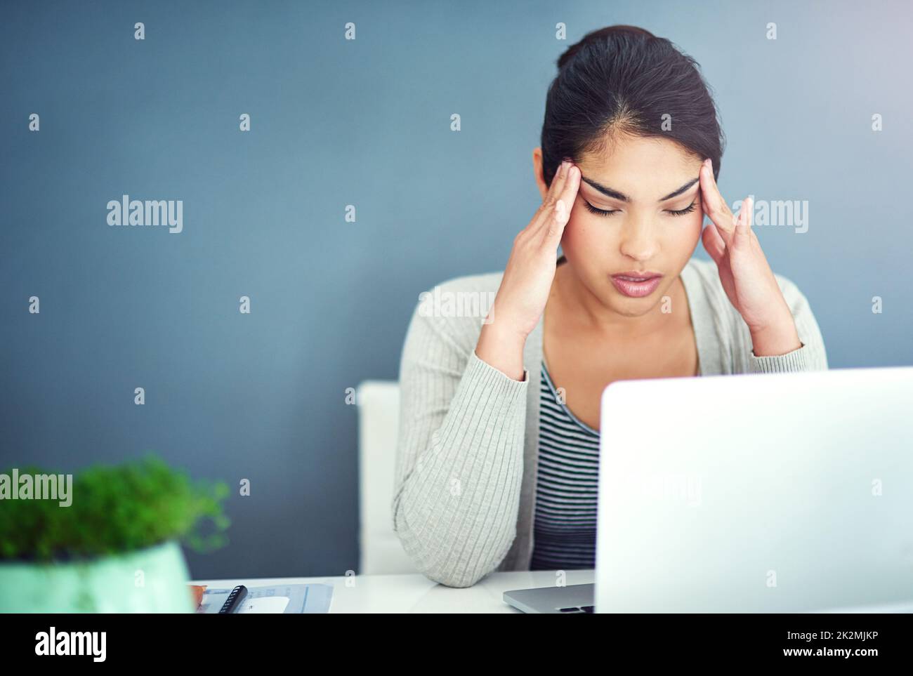 Dont let your job suck the happiness out of you. Shot of a businesswoman sitting with her hands on her head. Stock Photo