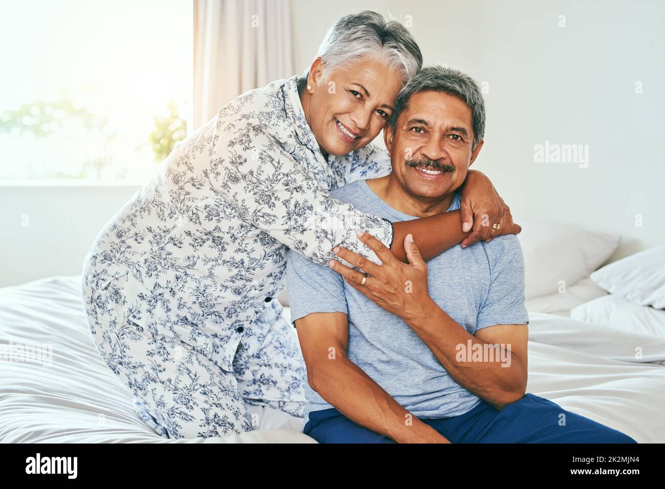 Life will never let us part. Portrait of a cheerful mature couple holding each other while being seated on a bed at home during the day. Stock Photo