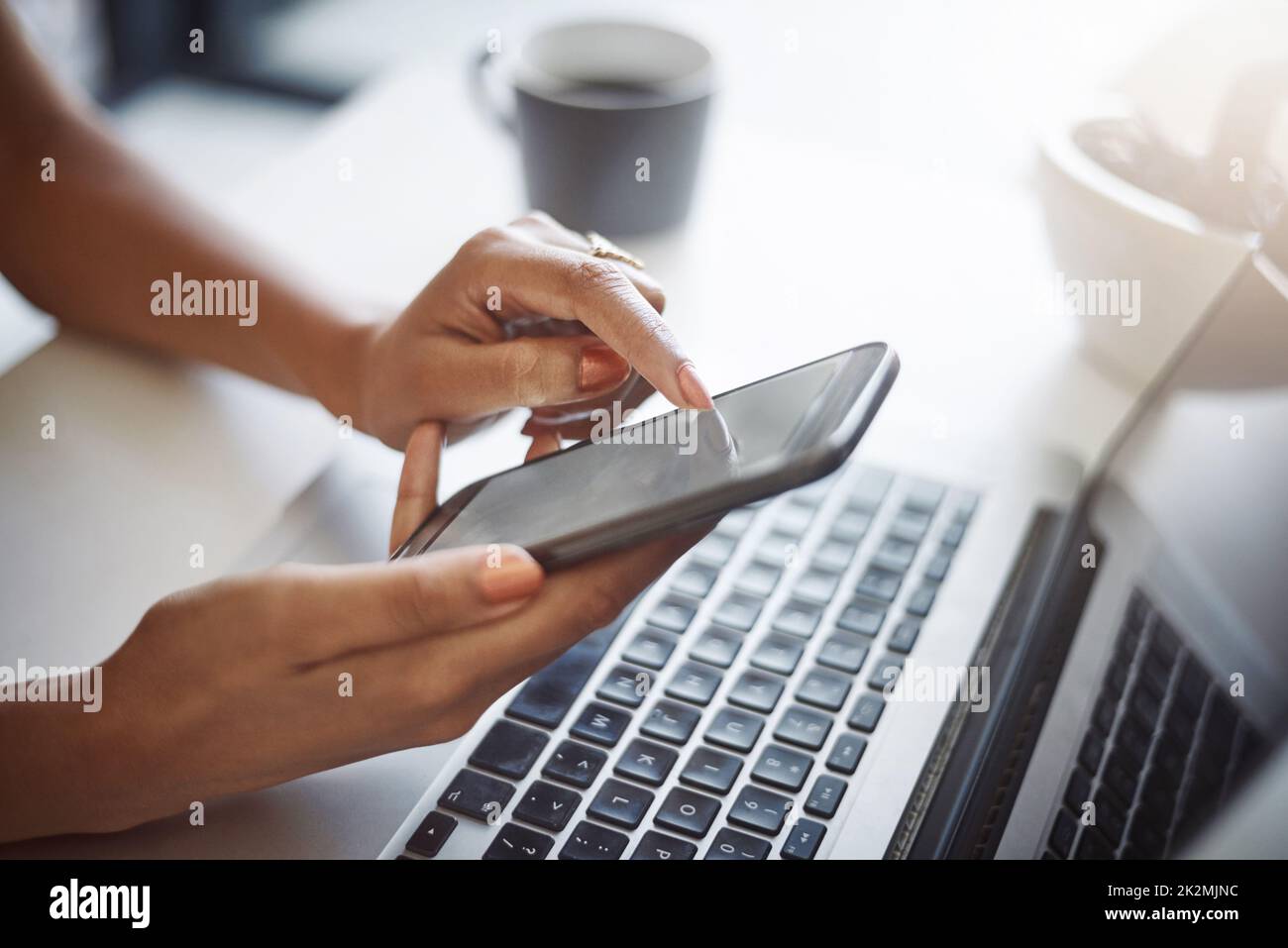 I can connect my multiple devices to have the same information. Closeup shot of an unrecognizable female designer using a cellphone in her home office. Stock Photo