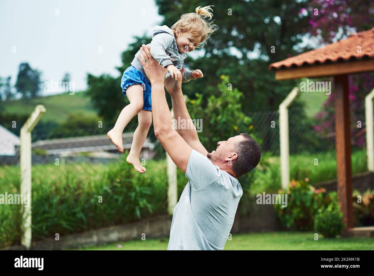 We have lift off. Shot of a cheerful little girl being lifted up in the air by her father outside during a cloudy day. Stock Photo