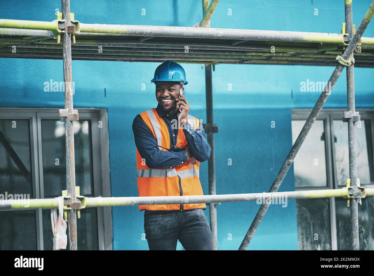 Were moving along right on track. Shot of a young man talking on a cellphone while working at a construction site. Stock Photo