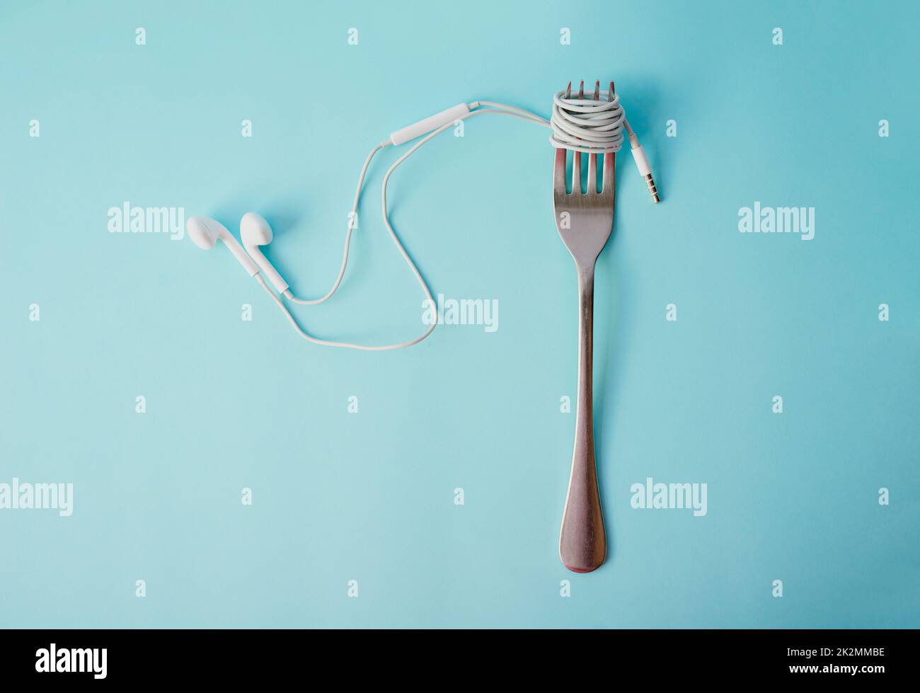 Soul food. Studio shot of earphones wrapped around a fork against a blue background. Stock Photo