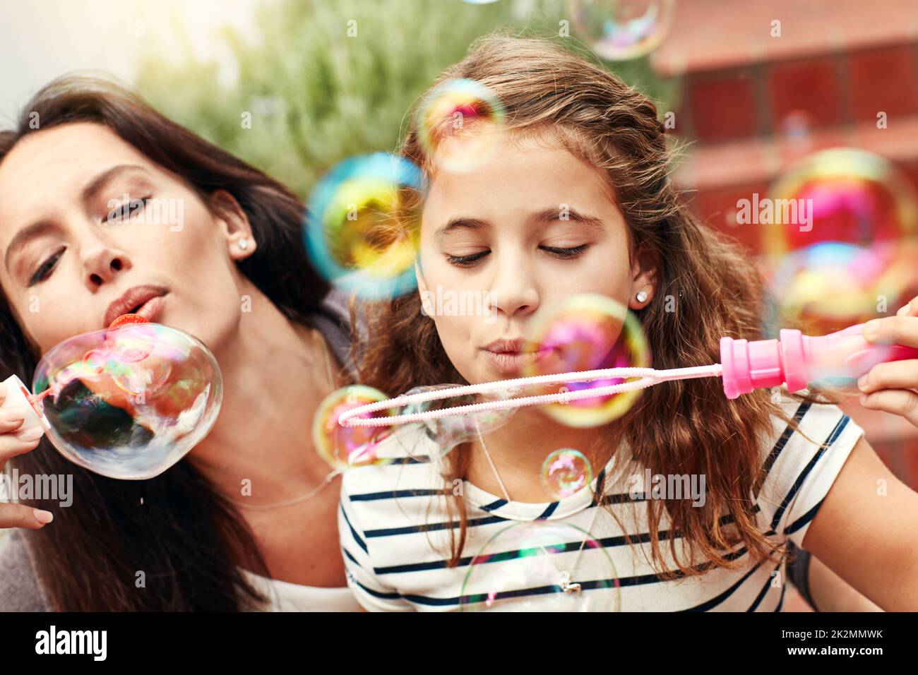 Having bubbles full of fun. A happy mother and daughter spending time together outdoors. Stock Photo