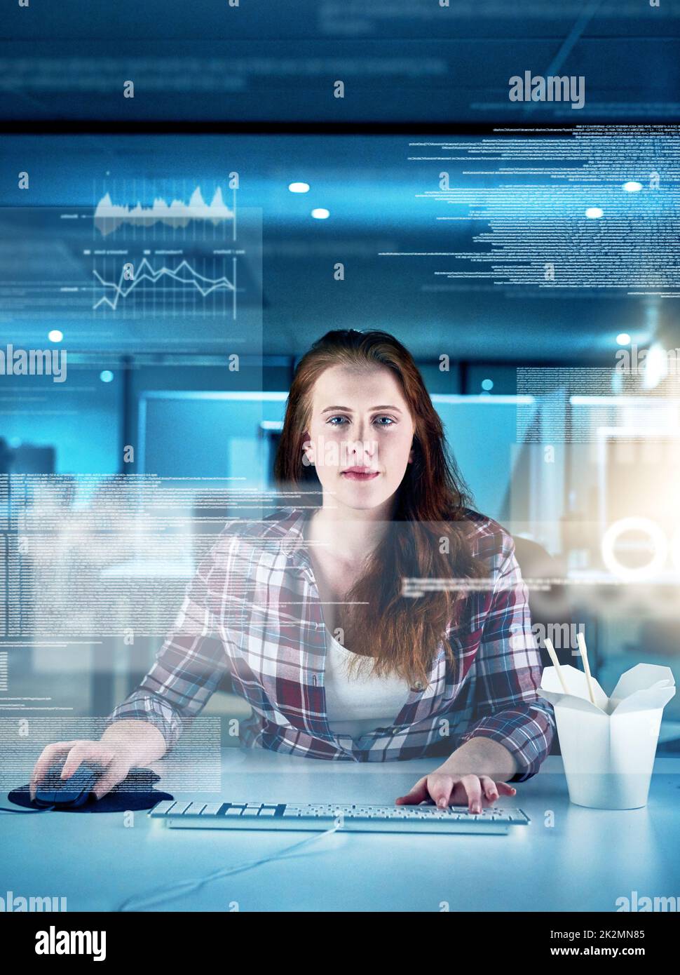 She is a human computer. Portrait of a focused young female programmer working on a computer in the office at work during the night. Stock Photo