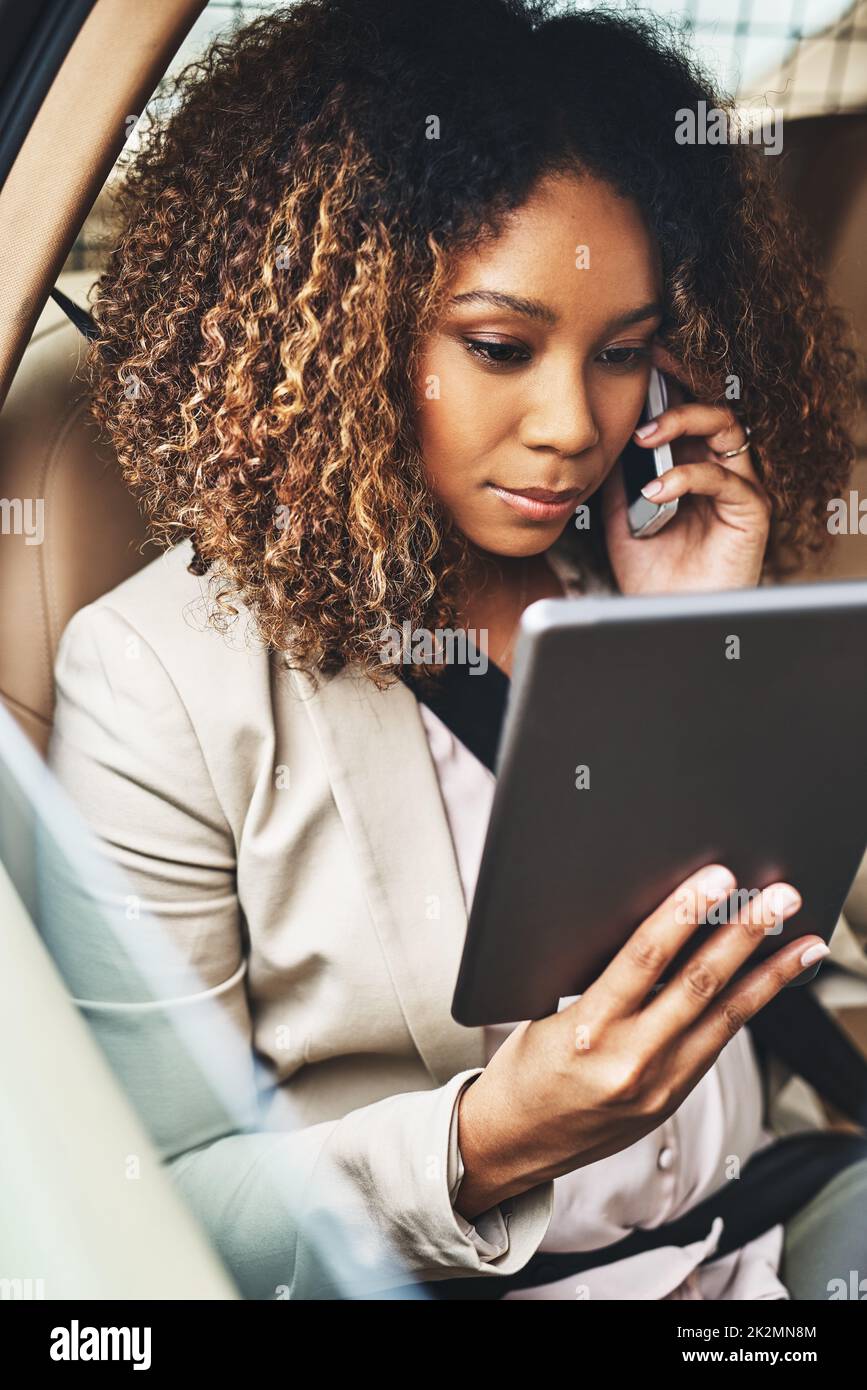Getting things done even when shes commuting. Shot of an attractive businesswoman on a call and using a tablet during her morning commute. Stock Photo