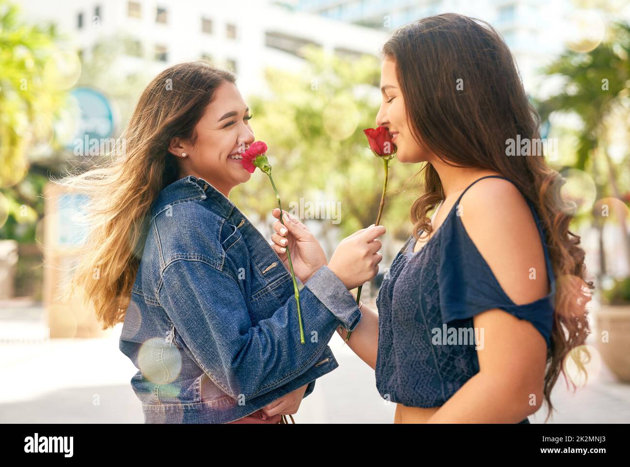 You my favourite person in the whole world. Cropped shot of two female best friends being smelling roses in the city. Stock Photo