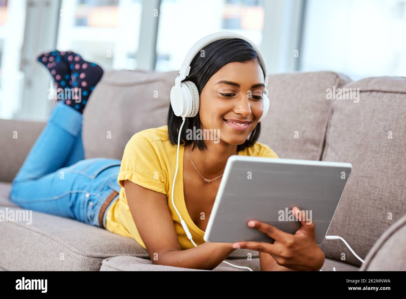 Listening to my favourite tunes. Shot of a teenage girl listening to music and using a tablet at home. Stock Photo