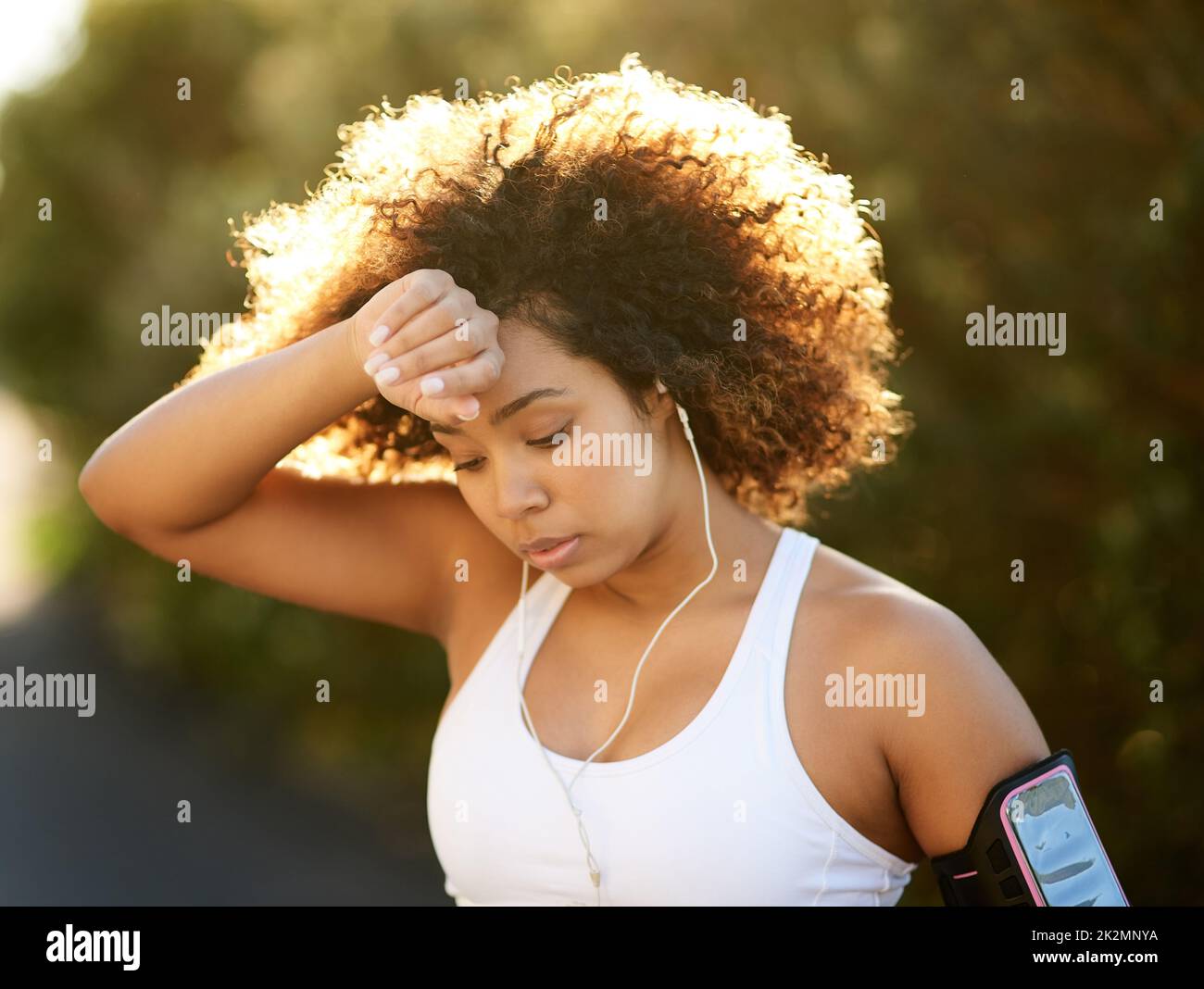 Working up a sweat. Shot of an attractive young woman wiping her brow during her workout. Stock Photo