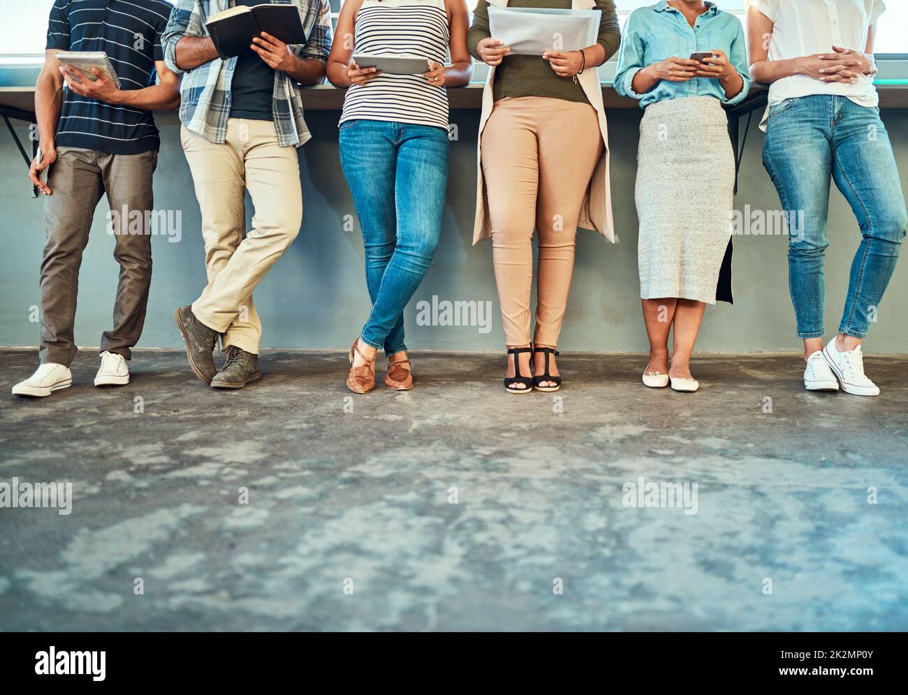 Brainstorming together as a team. Low angle shot of a group of unrecognizable work colleagues standing side by side in a straight line against a wall inside the office during the day. Stock Photo