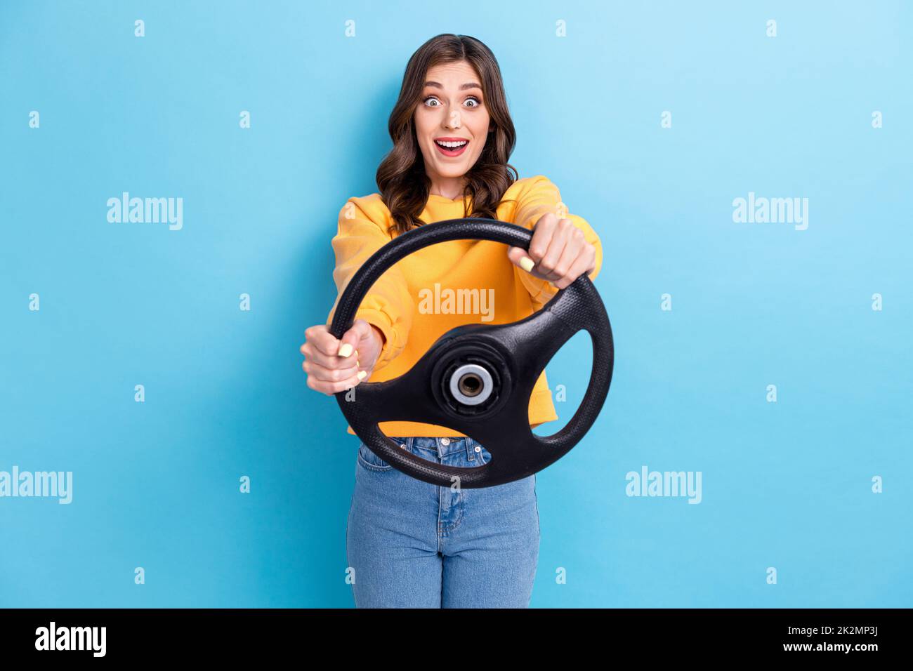 Photo portrait of stunning young woman hold steering wheel excited play simulator wear trendy yellow look isolated on blue color background Stock Photo