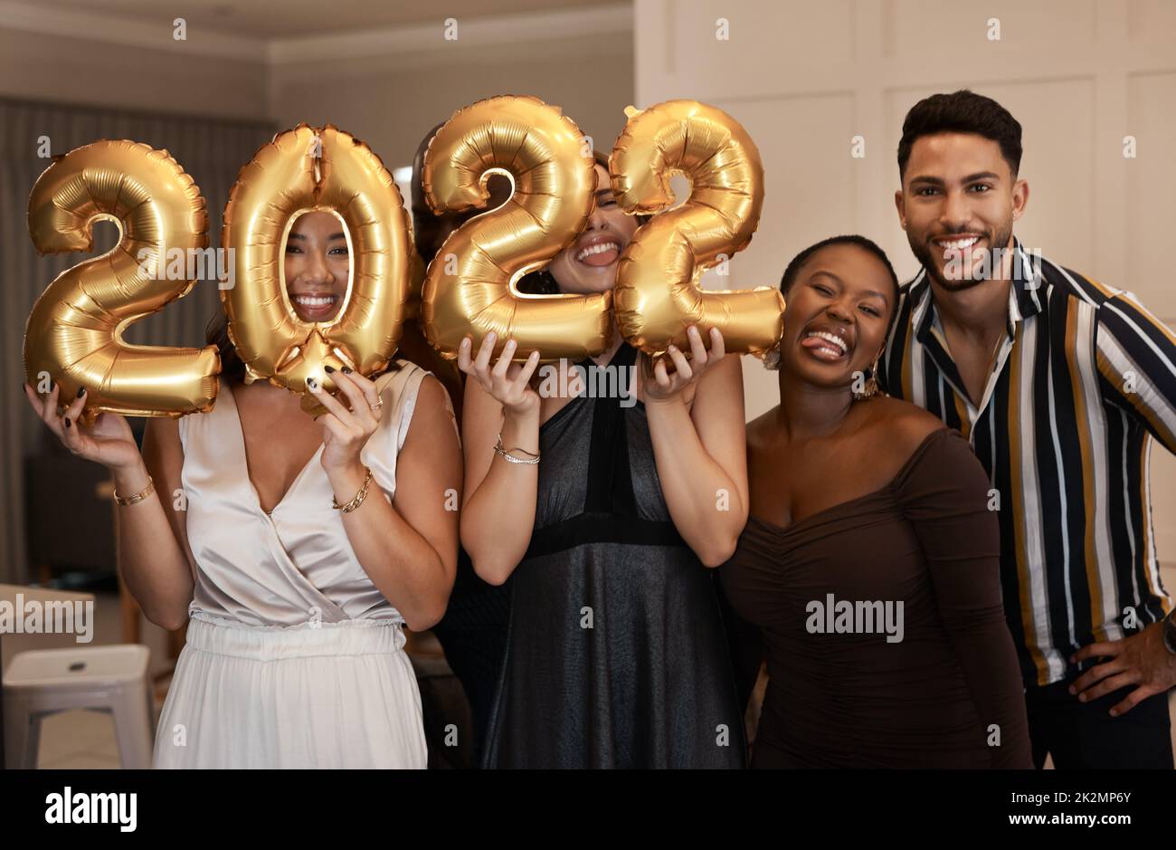 Were stoked for the New Year. Shot of a diverse group of friends standing together and holding up 2022 balloons during a New Years party. Stock Photo