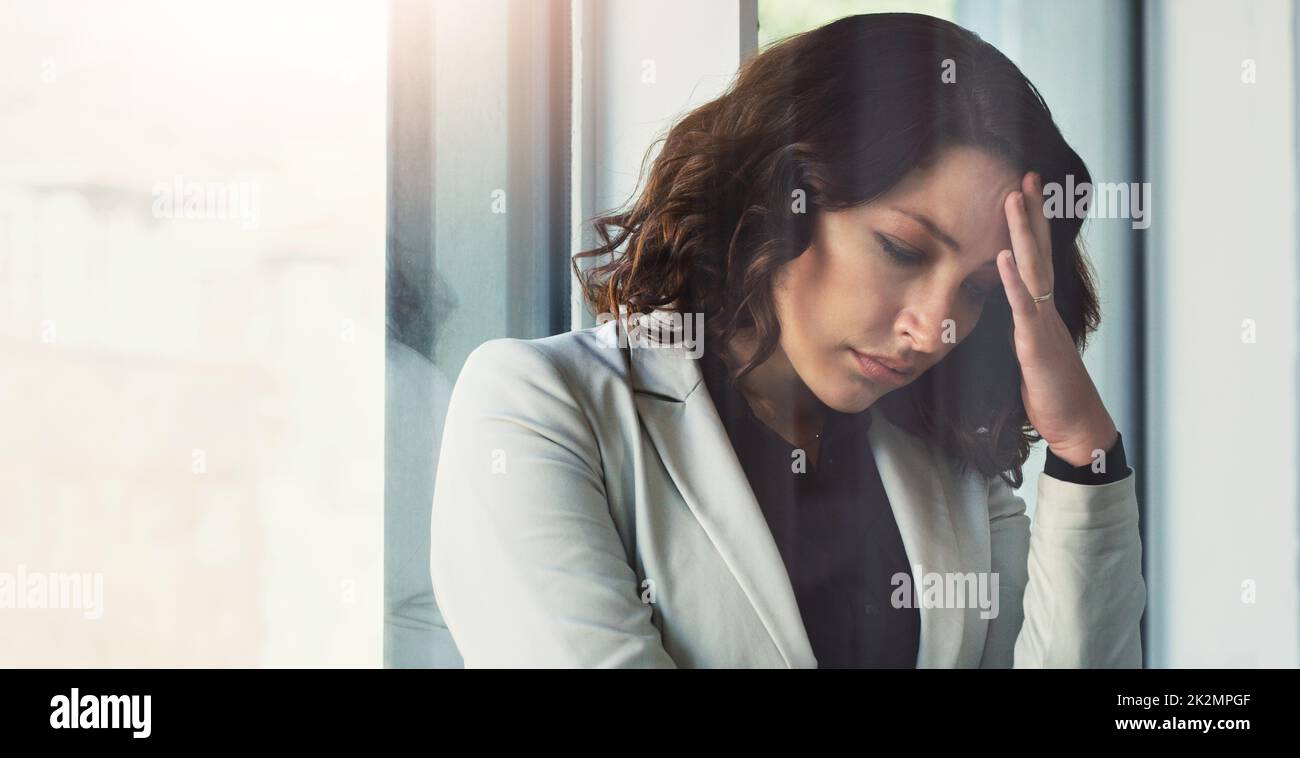 Depression is weighing her down. Cropped shot of an attractive young businesswoman feeling stressed out at work. Stock Photo