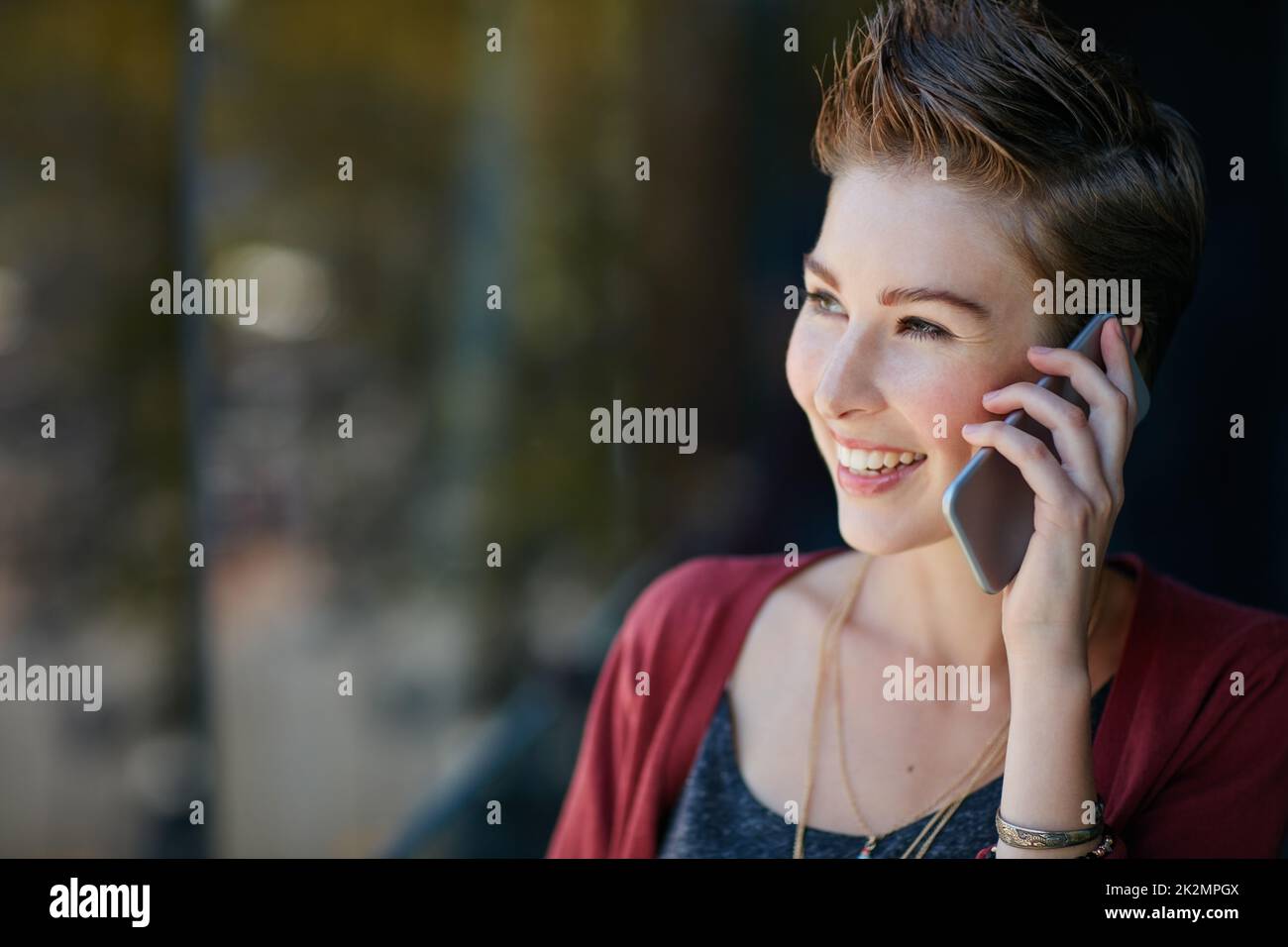 Thats just the news Ive been waiting for. Shot of an attractive young businesswoman using her cellphone while standing on her office balcony. Stock Photo