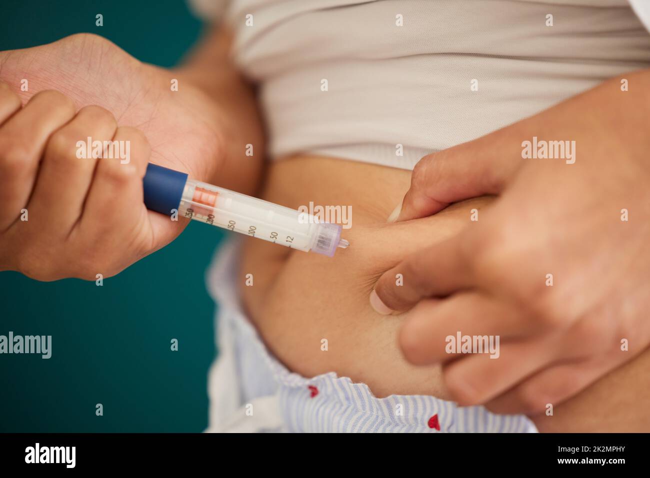 The body knows when insulin is required. Closeup shot of an unrecognizable woman injecting herself in the stomach with insulin at home. Stock Photo