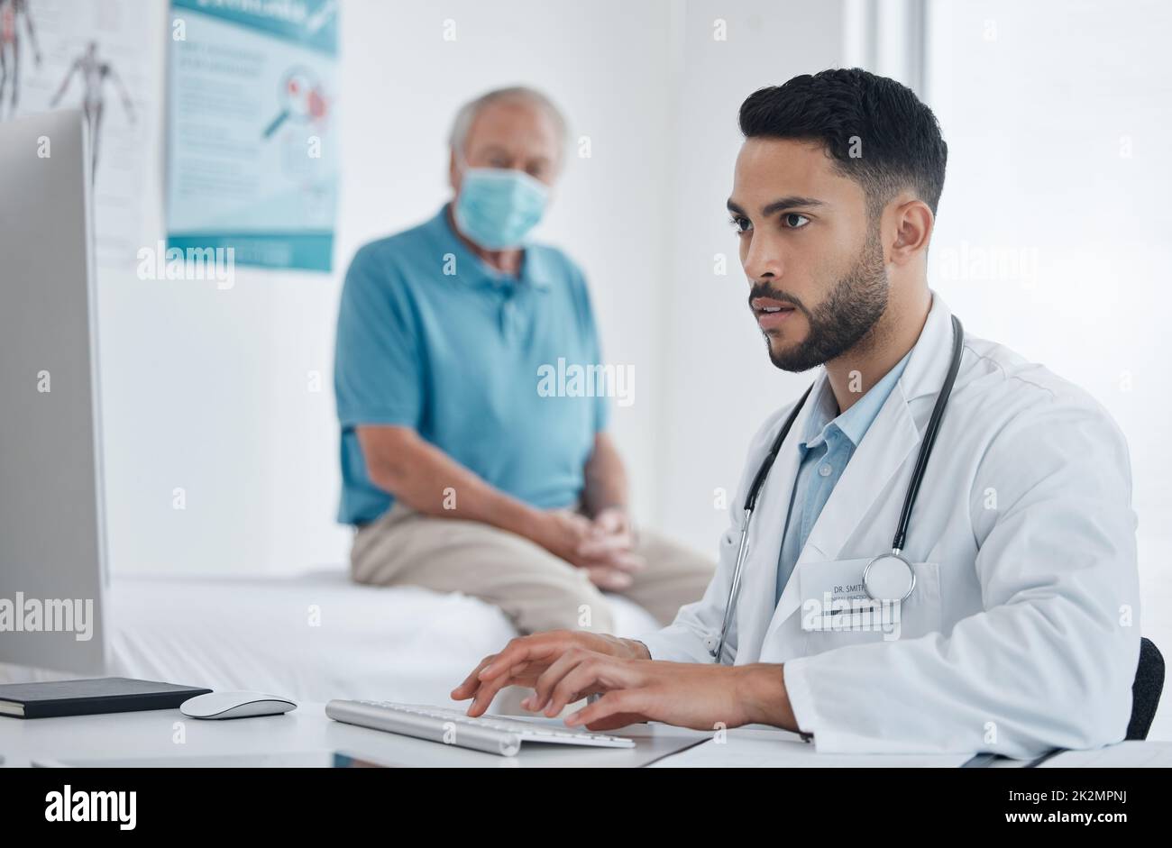 Im just checking if we have your information. Shot of a young doctor using computer in an office. Stock Photo