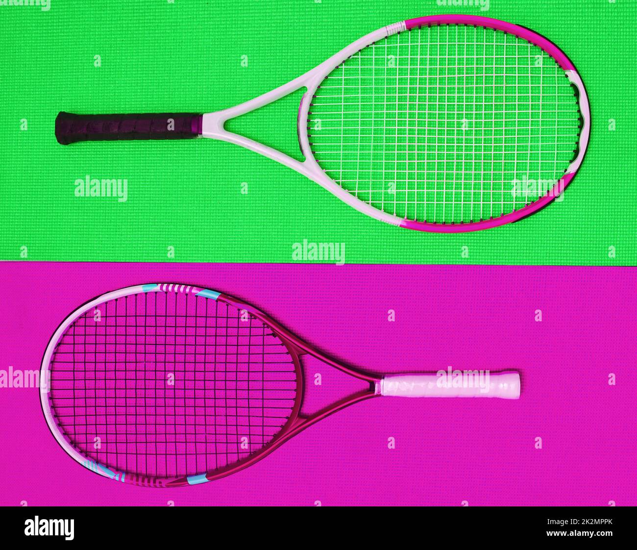 They are polar opposites. High angle shot of two tennis rackets placed together on top of a colourful background inside of a studio. Stock Photo