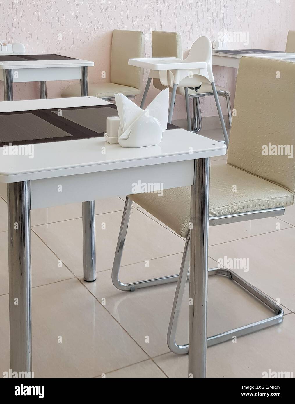 Stylish beige modern dining room interior with designer tables and