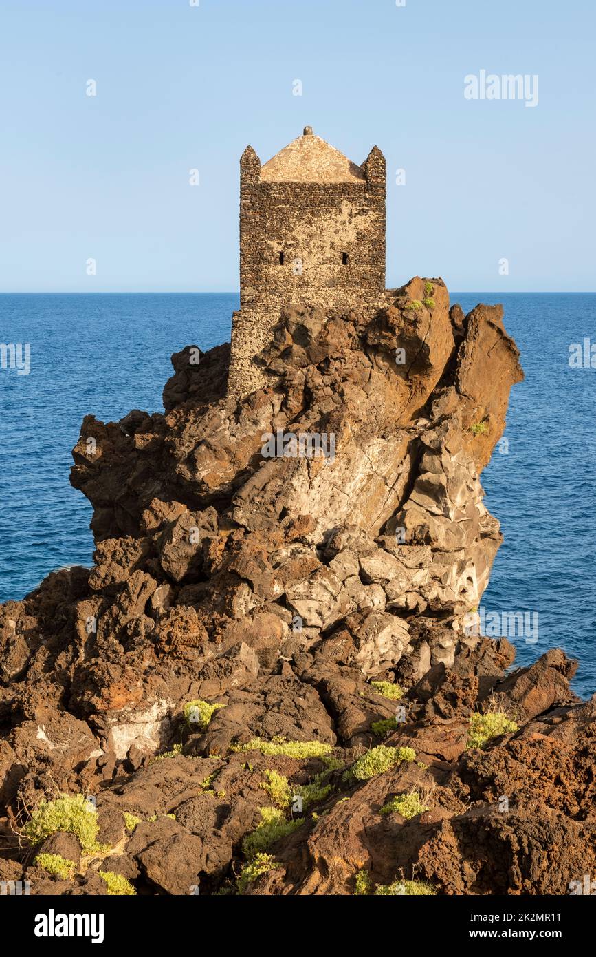 A medieval watchtower perched high on an outcrop of volcanic lava overlooking the Ionian Sea, near the little village of Santa Tecla, Acireale, Sicily Stock Photo