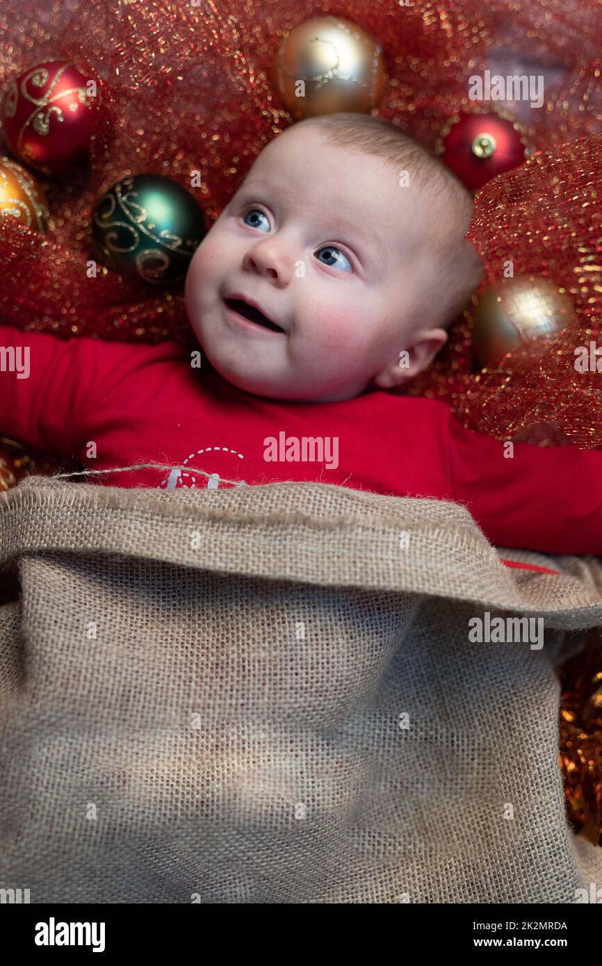 Cute happy baby surrounded with Christmas baubles Stock Photo