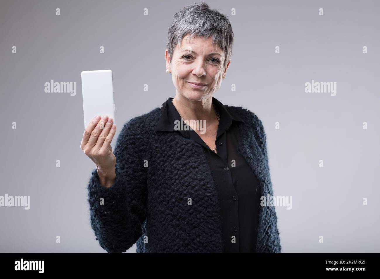 Older attractive woman holding up a mobile phone Stock Photo