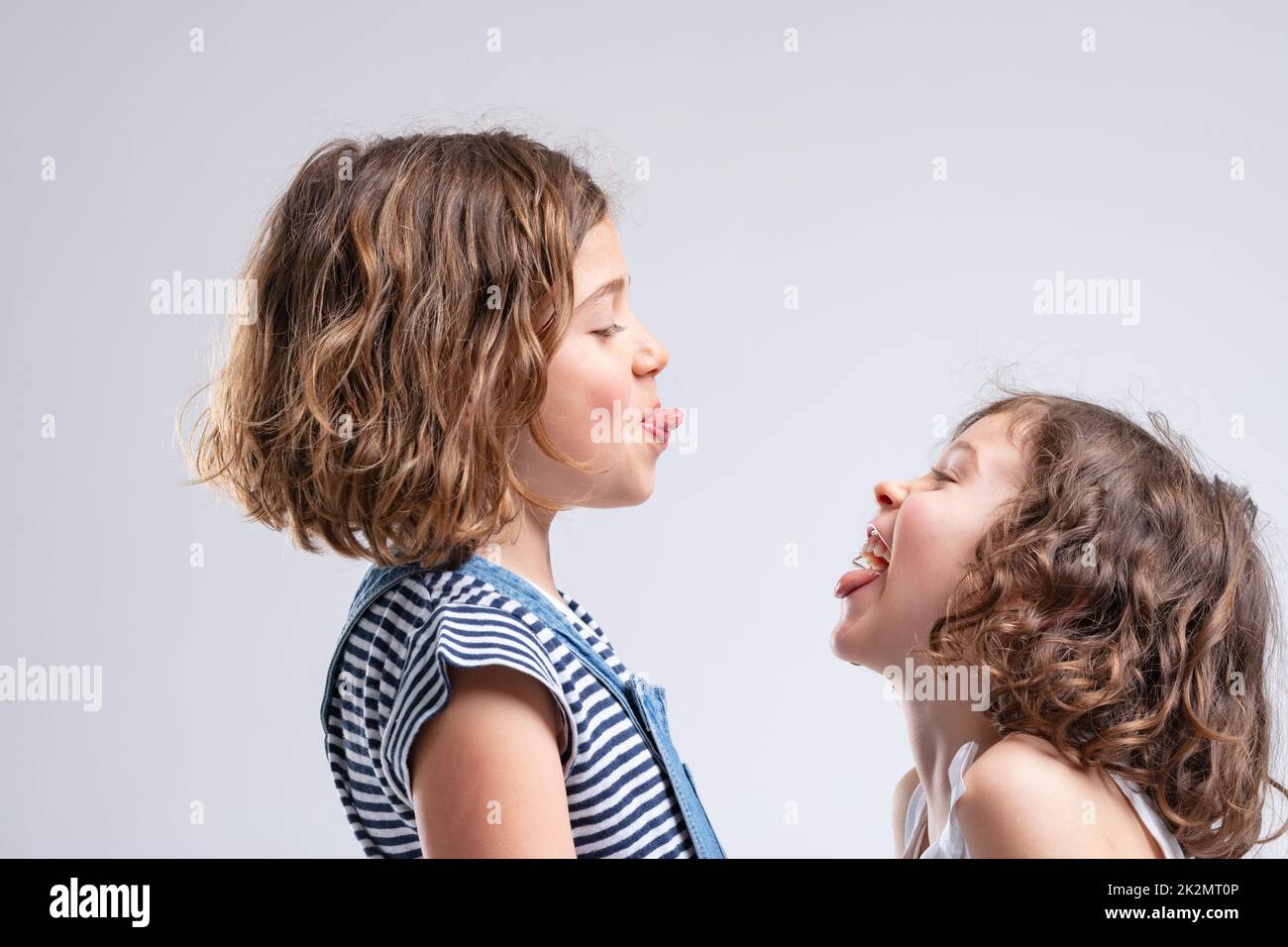 Two naughty young girls sticking out their tongues Stock Photo