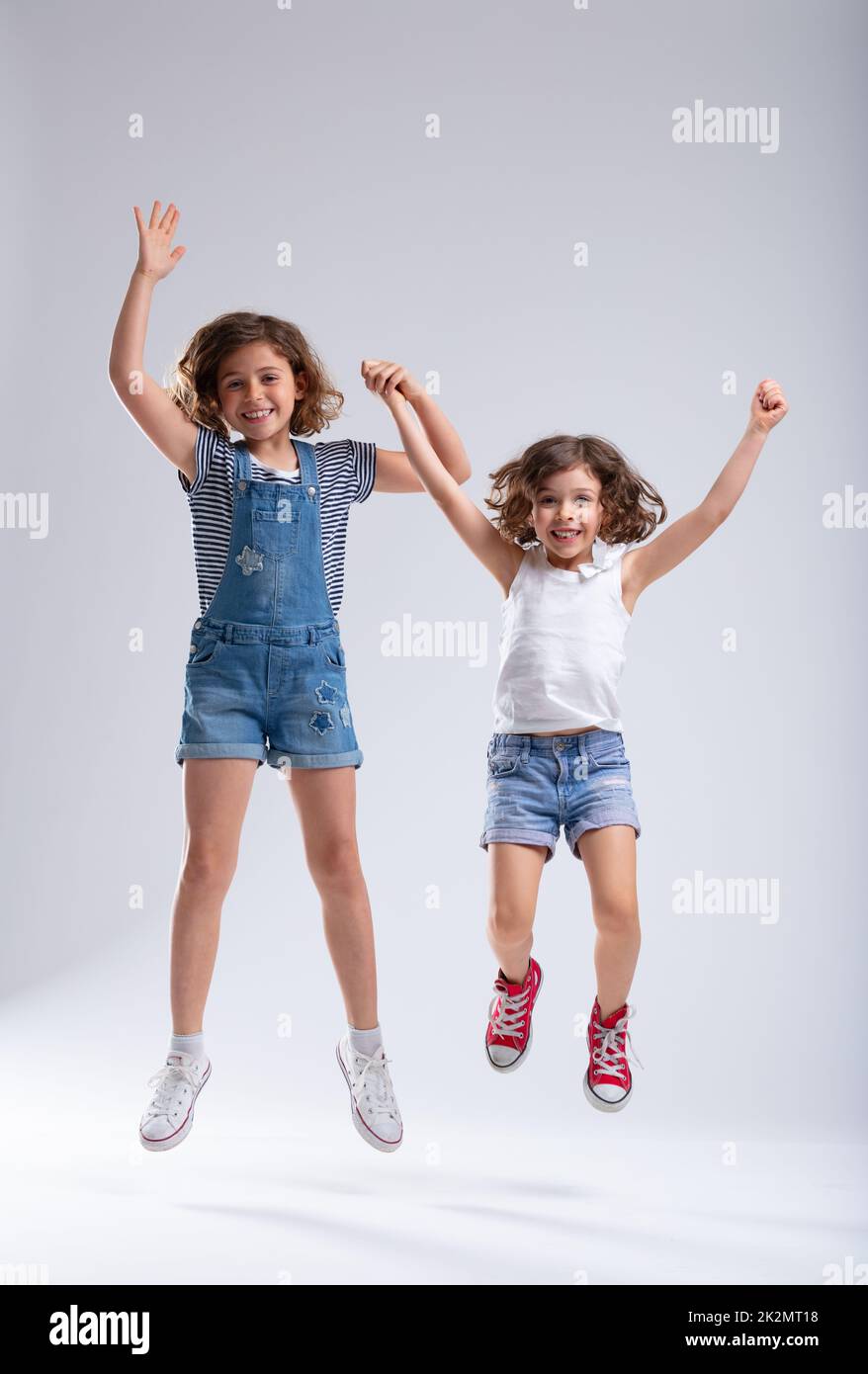 Two vivacious lively little girls jumping together Stock Photo