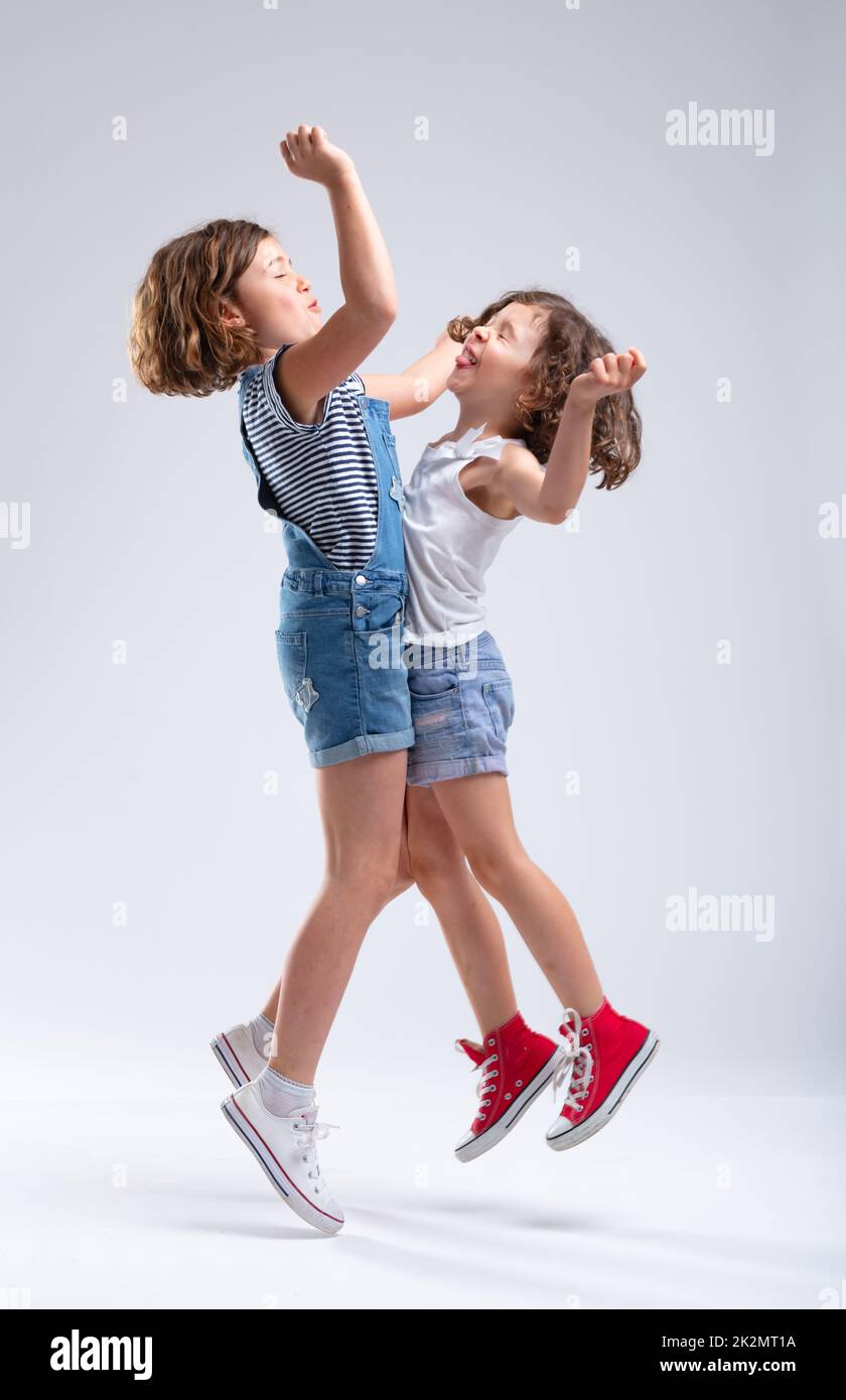 Two joyful hyperactive young sisters jumping Stock Photo