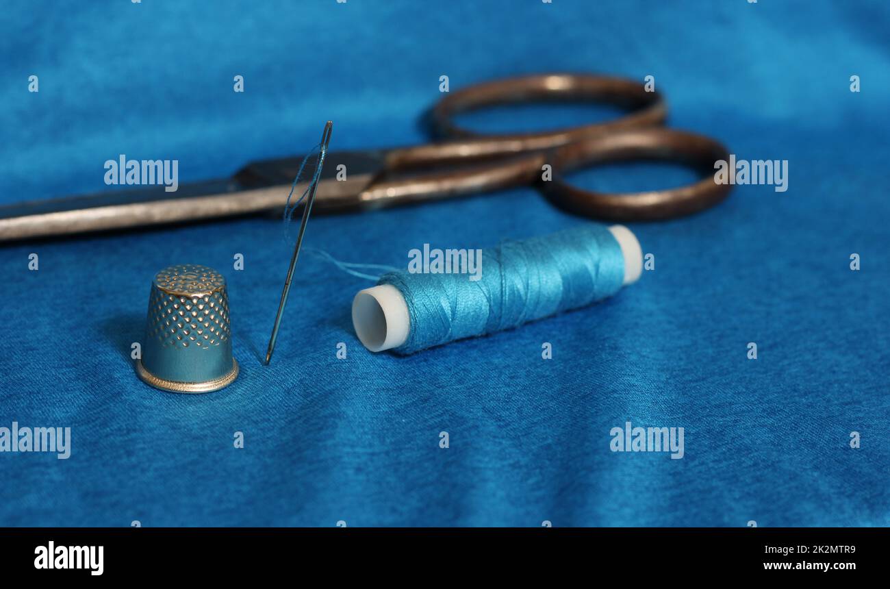 Spool of Blue Thread, Thimble and Needle on Blue Fabric Stock Photo - Alamy
