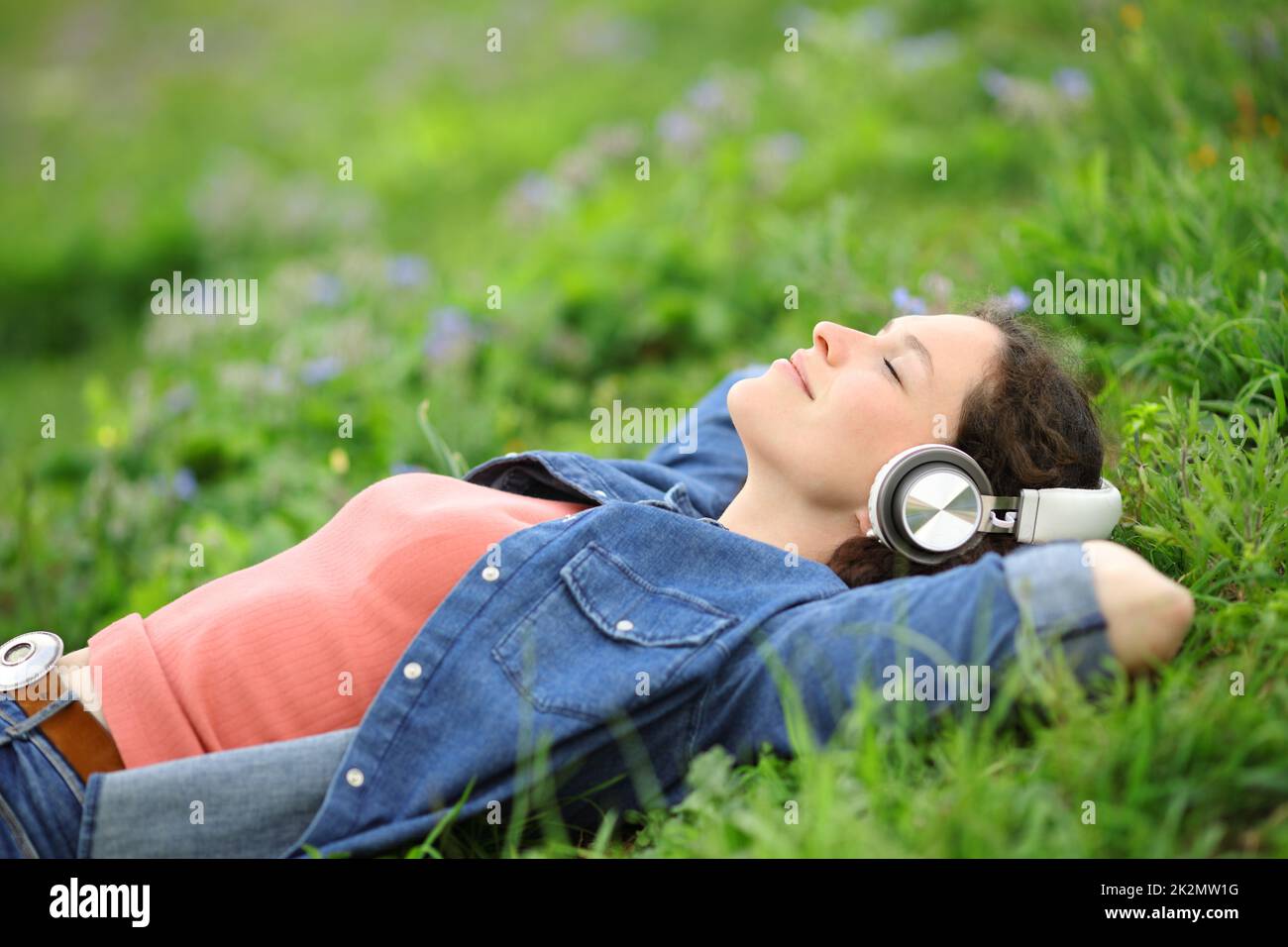 Relaxed woman lying on the grass listening to music Stock Photo - Alamy