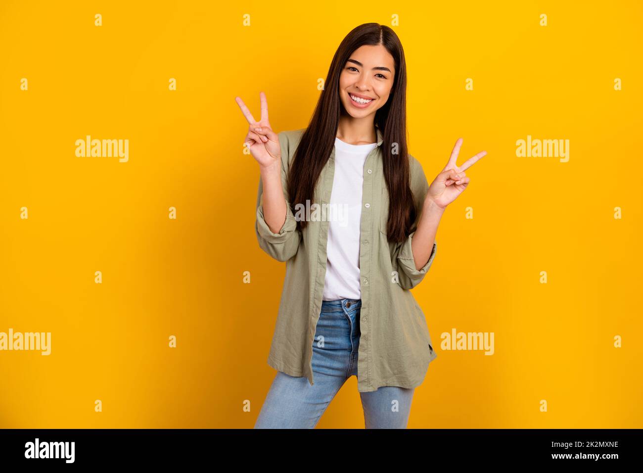 Photo of cheerful stunning asian female show v sign say hello meet her boyfriend isolated on yellow color background Stock Photo