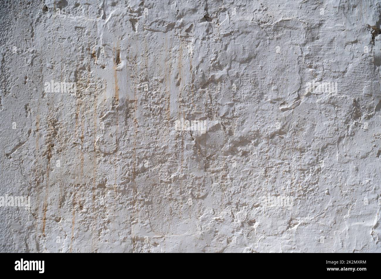 A old white painted wall with peeling paint and whitewash on an old building in Spain.  An abstract texture or background Stock Photo