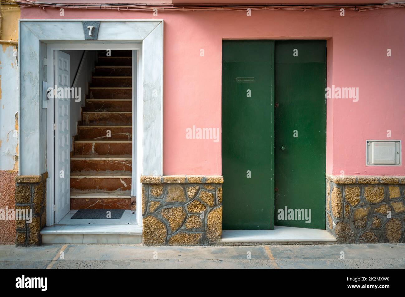 A stairway and door in an old building painted pink and green in Spain Stock Photo