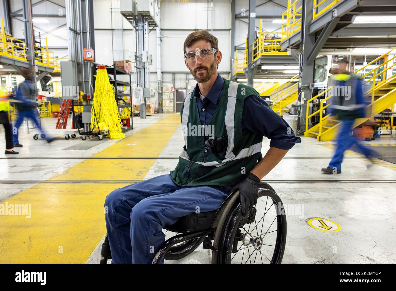 Male transit worker in wheelchair working in maintenance facility Stock