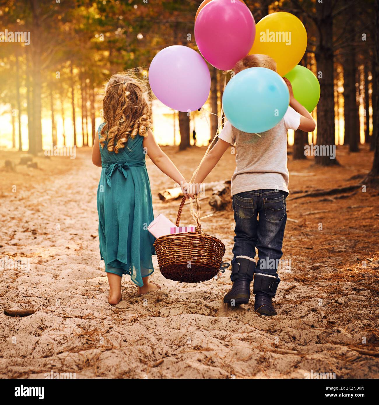 Best friends stick together. Shot of an unrecognizable little boy and girl holding a basket and balloons while walking outside in the woods. Stock Photo