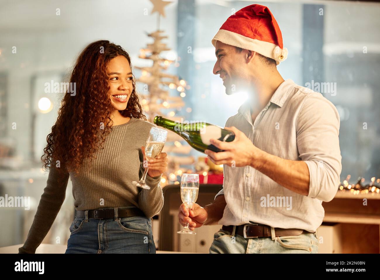 Whats a celebration without the champagne. Shot of two young businesspeople celebrating Christmas at work. Stock Photo