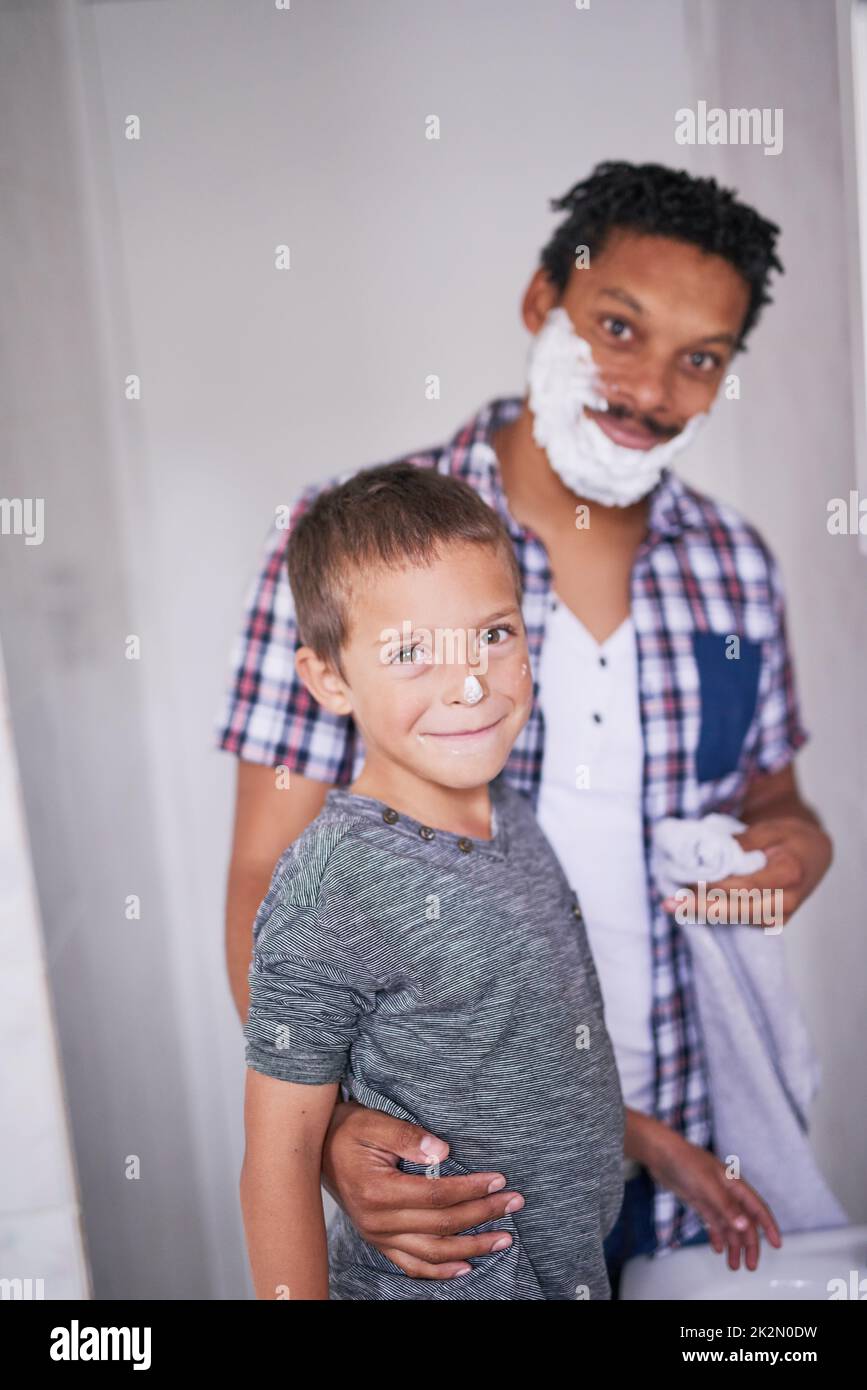 Special moments like these always brings smiles. Portrait of a father and son shaving together in a bathroom. Stock Photo