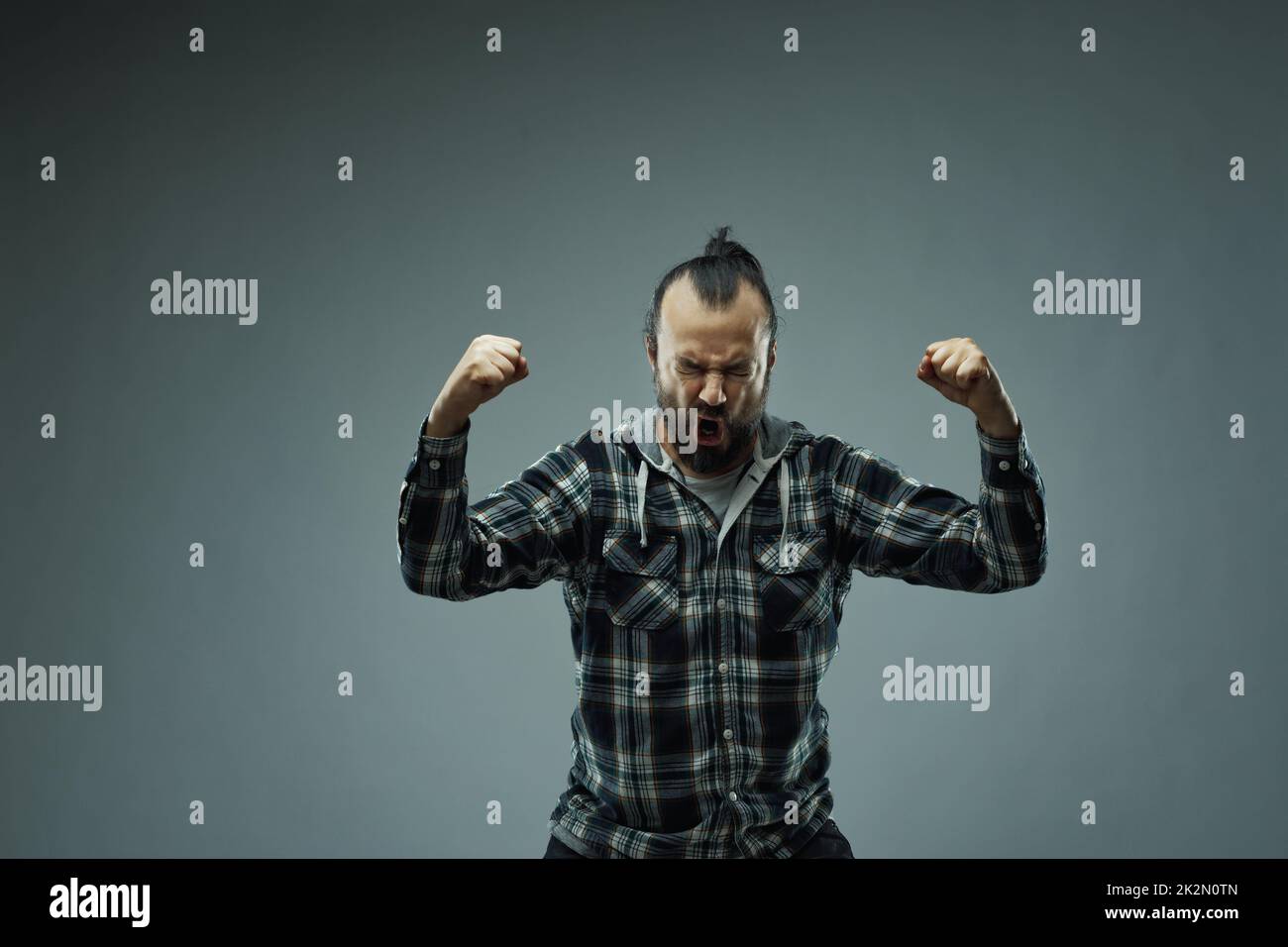 Man in check shirt raising hands in triumph Stock Photo