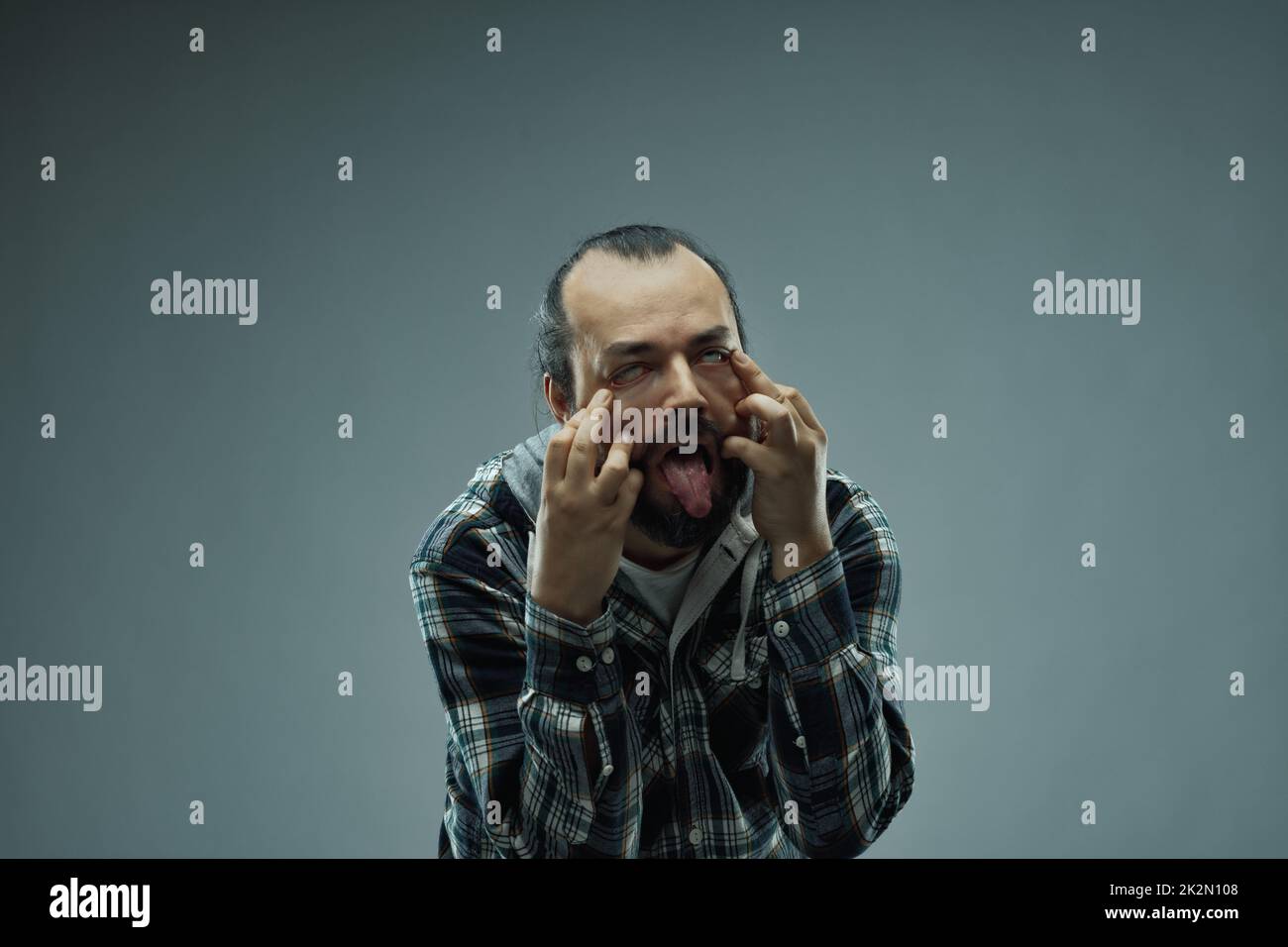 Imbecilic or manic man pulling a grotesque face at the camera Stock Photo