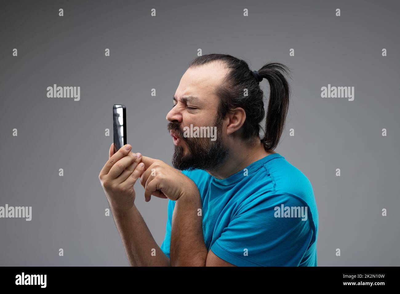 Man grimacing while using smartphone Stock Photo