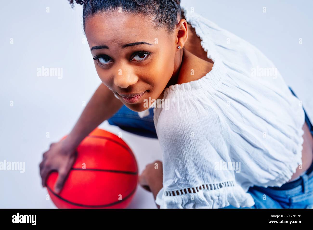 Athletic young Black woman crouching down over a red ball Stock Photo