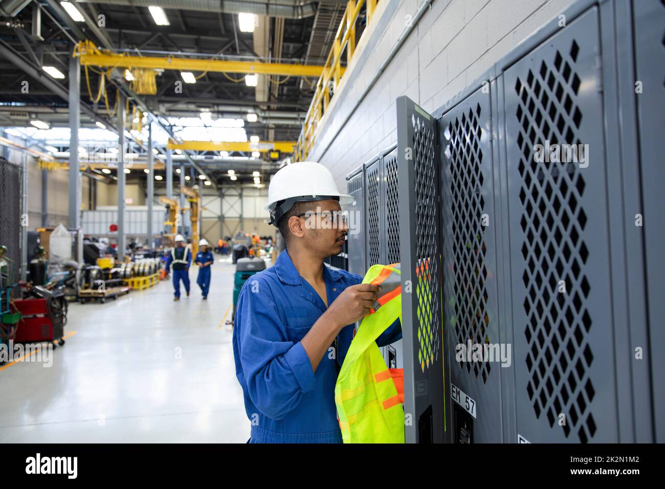 Male transit worker reaching for reflective vest in locker Stock Photo
