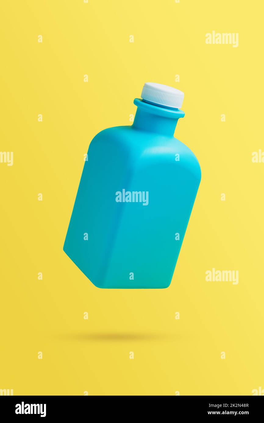 Falling blue bottle with household chemisrty. Isolated on yellow background Stock Photo